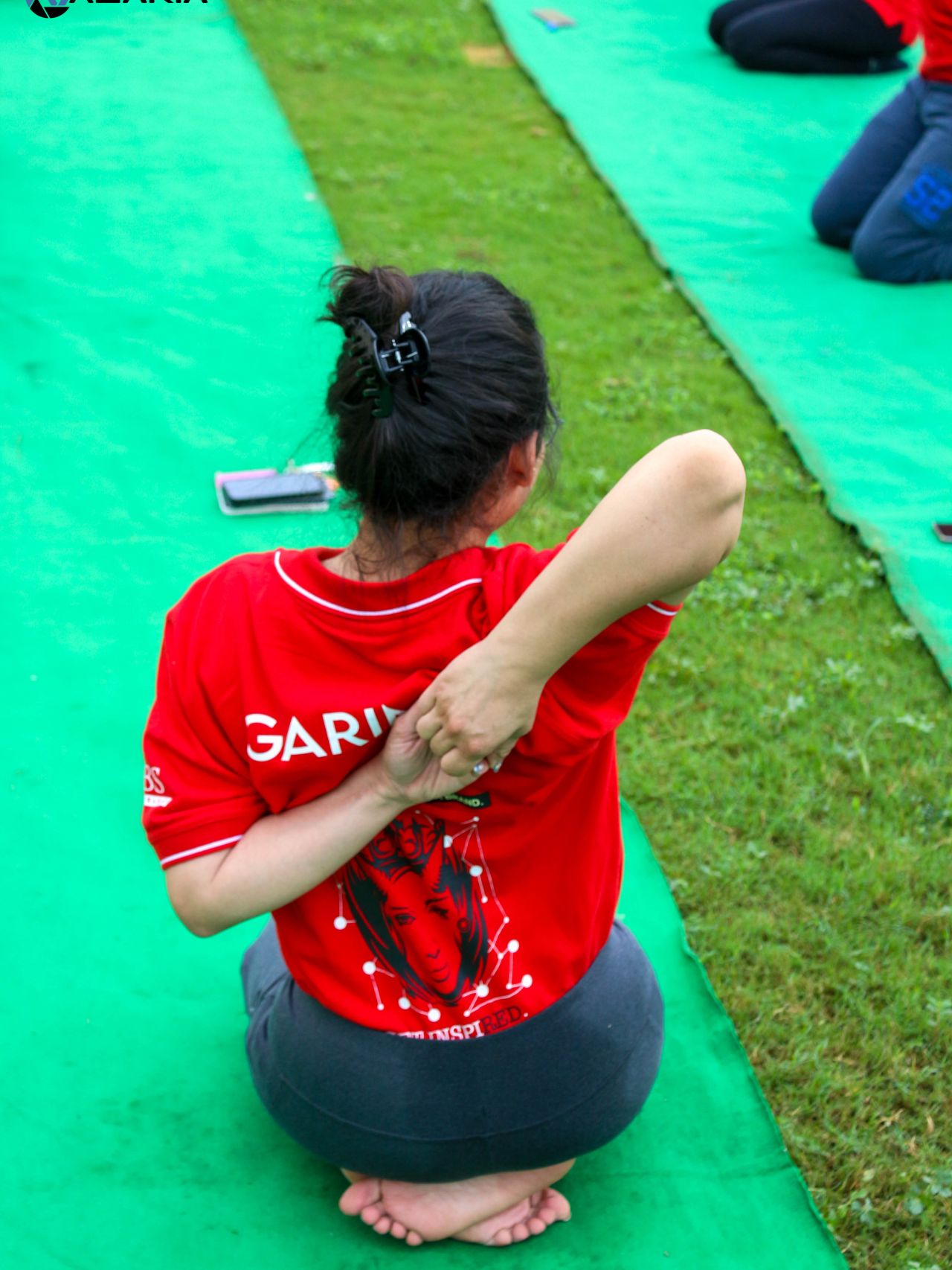 Back view of a yoga practitioner performing Gomukhasana during an outdoor yoga practice session by Yoganta.