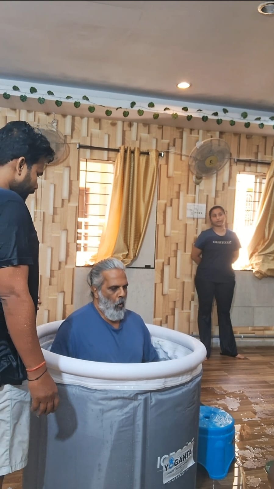 Hari Subramanyam in the ice bath with a trainer standing beside the tub at the Yoganta Ice Bath Instructor Course (YCIBI) workshop in Hyderabad.