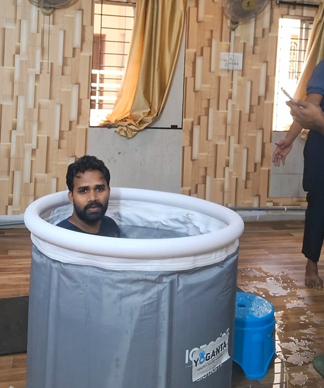 Raushan Yoganta seated in a Yoganta ice bath tub at the Yoganta Ice Bath Instructor Course (YCIBI) workshop in Hyderabad, with a participant standing nearby.