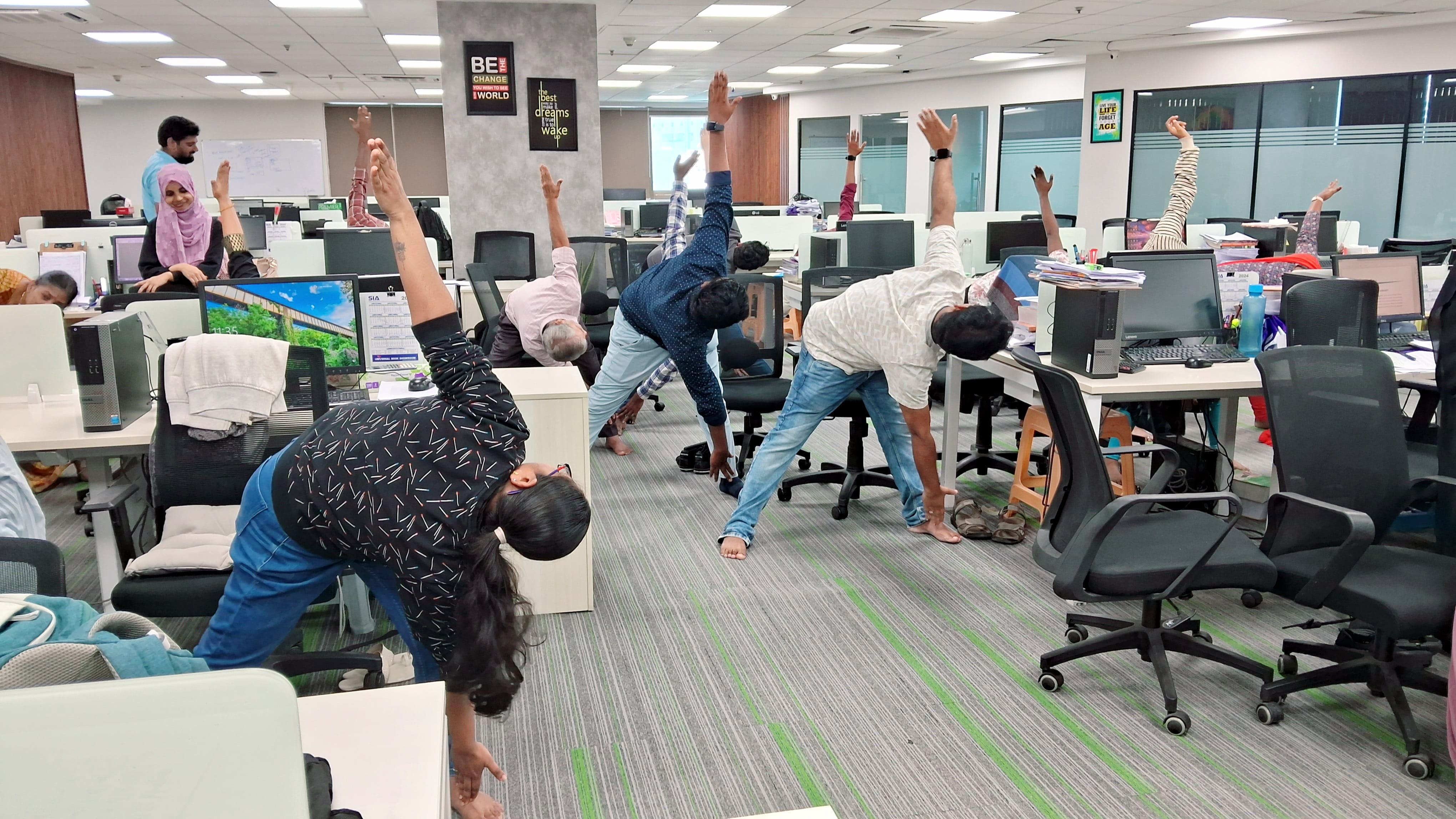 Corporate employees practicing Trikonasana during a Yoganta wellness session.