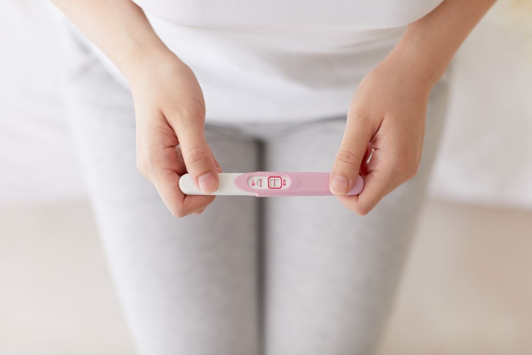a woman looking at the pregnacy kit to see the pregnacy test result after practising fertility yoga